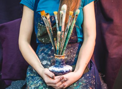 Closeup of female artist hands with paintbrushes